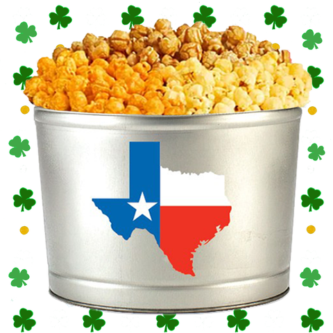 Metal popcorn tin with Texas flag design filled with popcorn, surrounded by shamrock decorations.