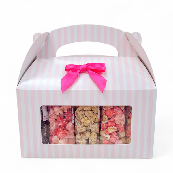 Gift box with pink and white striped design and a pink bow, containing 10 different flavors of popcorn inside.